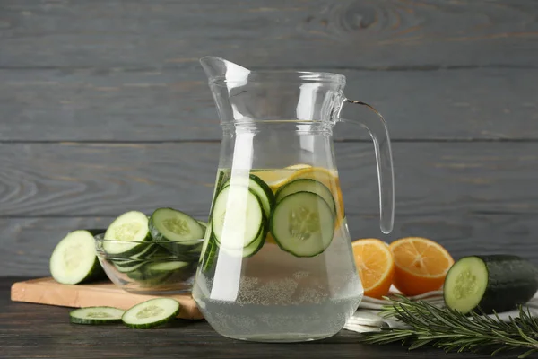Composition with cucumber water in jug on wooden background, clo