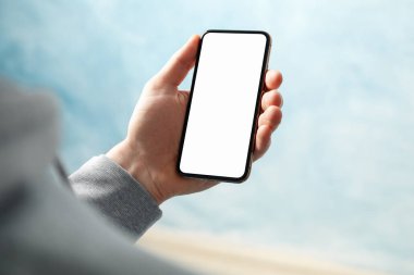 Mavi arkaplana karşı boş ekranlı telefonu tutan adam