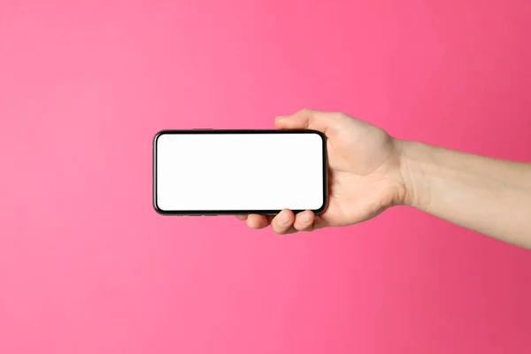 Pembe arka planda bir kadın telefonu tutuyor. Boş ekran