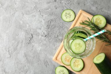 Gri zemin üzerinde bir bardak salatalık suyu olan kompozisyon, üst görünüm.