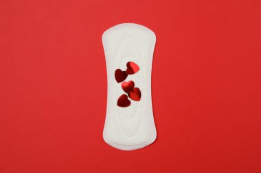 Kırmızı arka planda küçük kalpleri olan hijyenik ped.
