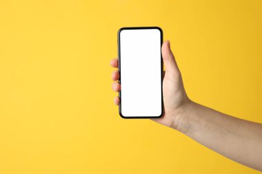 Sarı arka planda boş ekranı olan kadın el ele tutuşması.