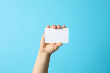 Mavi arka planda boş bir kartvizit tutan kadın.