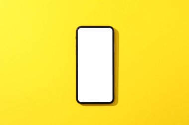 Sarı arkaplanda boş ekranlı telefon, üst görünüm