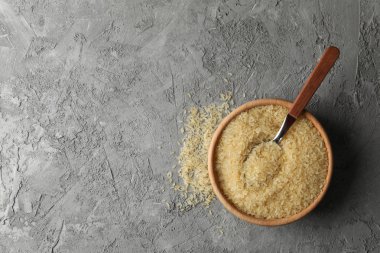 Gri arka planda pirinç ve kaşık kasesi, üst manzara.