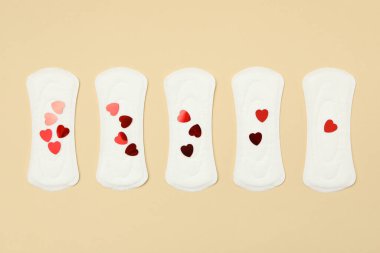 Bej arka planda küçük kalpleri olan hijyenik pedler.