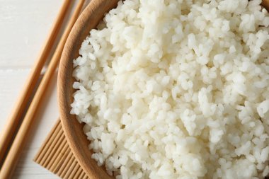 Kaynamış pirinç ve ahşap arka planda çubuklarla dolu bir kase.