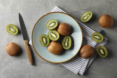 Gri masa üzerinde olgun kivi tabağı ile kompozisyon, üst görünüm