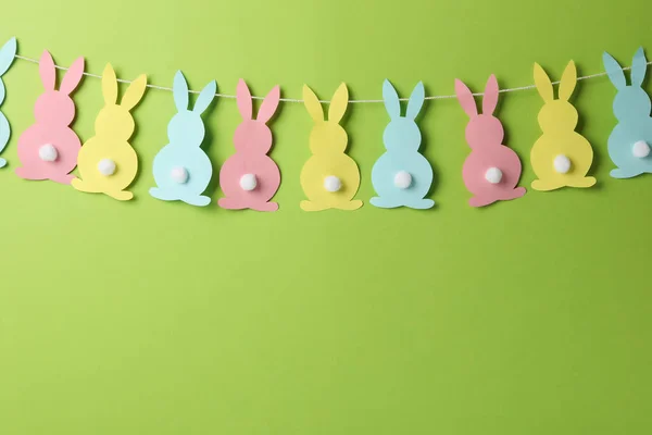 Twine with colorful bunnies on green background, space for text