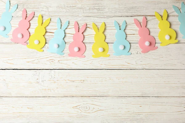 Twine with colorful bunnies on wooden background, space for text