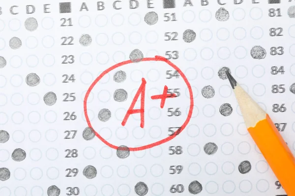 Test score sheet with answers, grade A+ and pencil, close up