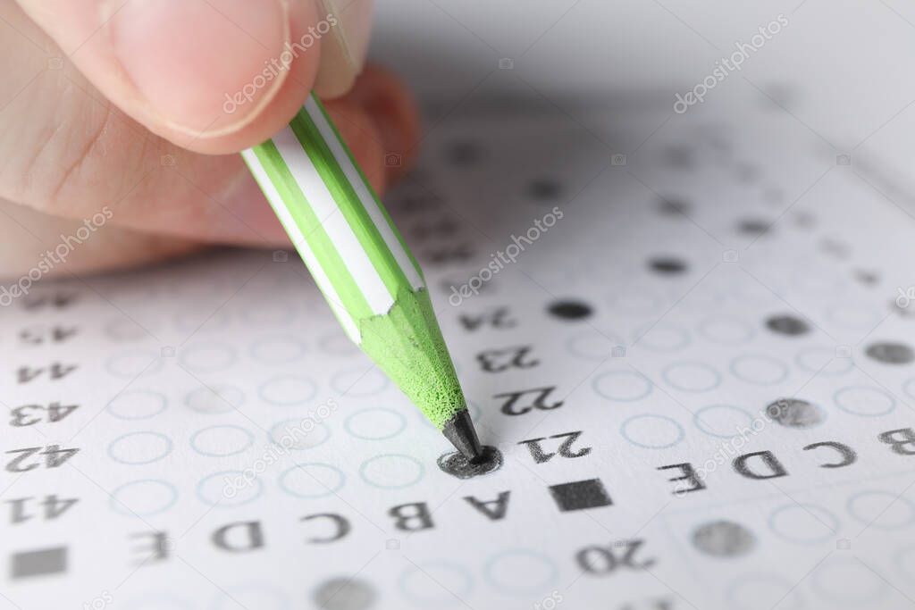 Student fills answers test sheet, close up