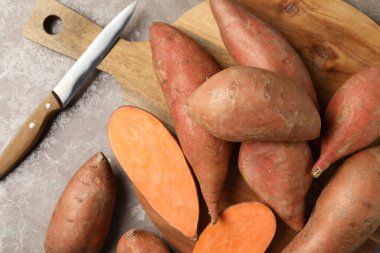 Tatlı patates, tahta ve bıçak gri arka planda, üst manzara