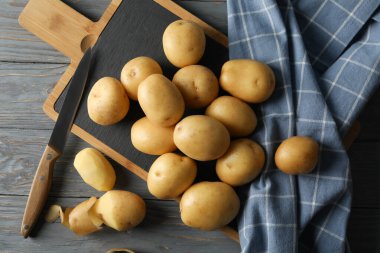 Genç patates, tahta, havlu ve bıçak ahşap arka planda, üst manzara