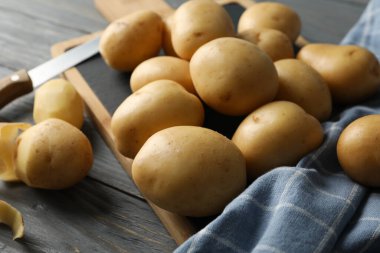 Genç patates, tahta, havlu ve bıçak ahşap arka planda, kapatın.