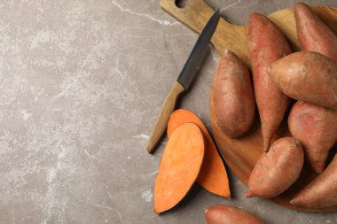 Tatlı patates, tahta ve bıçak gri arka planda, üst manzara