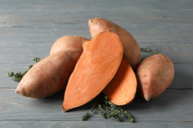 Tahta arka planda tatlı patates ve kekik, yakın plan.