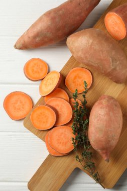 Beyaz ahşap arka planda tatlı patates ve tahta, üst manzara.