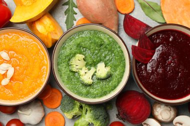 Gri arka planda sebze çorbaları ve malzemeler, üst görünüm