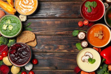 Ahşap arka planda sebze çorbası ve malzemeler, üst manzara.