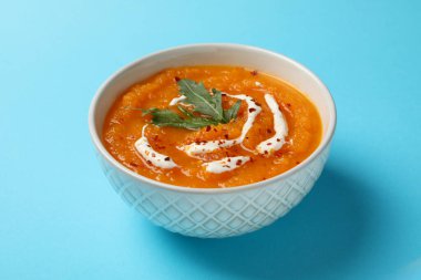 Mavi arka planda balkabağı kremalı çorba, yakın plan.