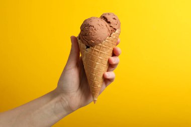 Kadın eli sarı arkaplanda dondurma tutuyor, metin için boşluk