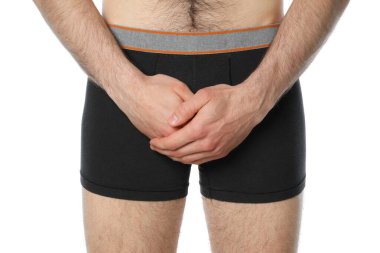 Kasıklarını tutan adam, beyaz arka planda izole edilmiş. Erkek Sağlığı