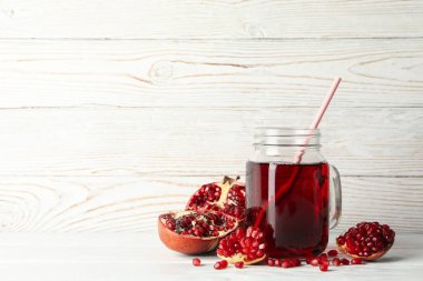 Ahşap zemin üzerinde nar ve bir kavanoz meyve suyu. Olgun meyve