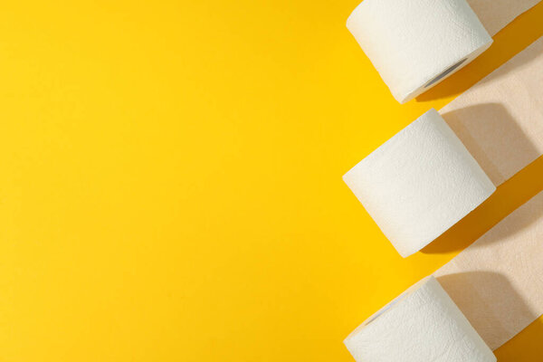 Toilet paper on yellow background, space for text