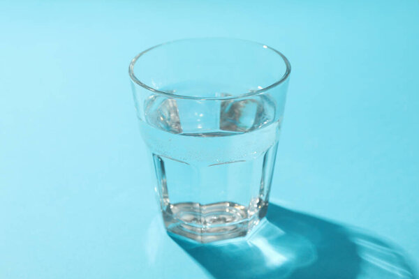 Glass of water on blue background, close up