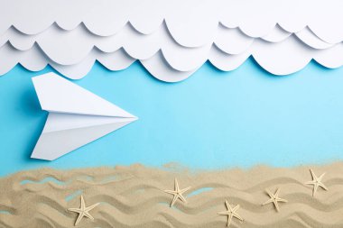 Kağıt bulutlar ve uçak, mavi arka planda deniz yıldızları olan kum. Tatil