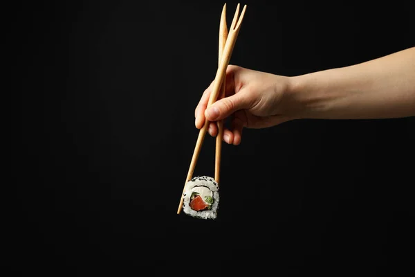 Vrouwelijke Hand Met Eetstokjes Houden Sushi Roll Zwarte Achtergrond Japans — Stockfoto