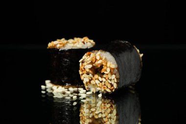 Siyah aynalı arka planda lezzetli suşi ruloları. Japon yemeği.