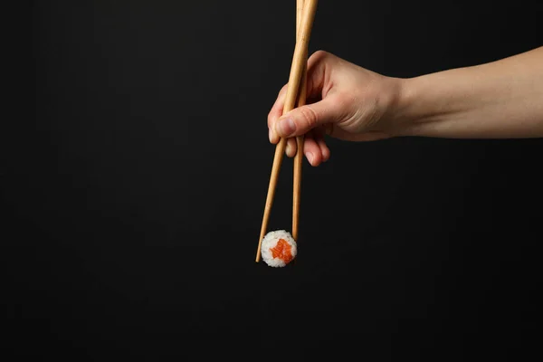 Vrouwelijke Hand Met Eetstokjes Houden Sushi Roll Zwarte Achtergrond Japans — Stockfoto