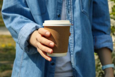 Kadın elinde boş kahve fincanı tutuyor. Bahar çiçek açıyor.