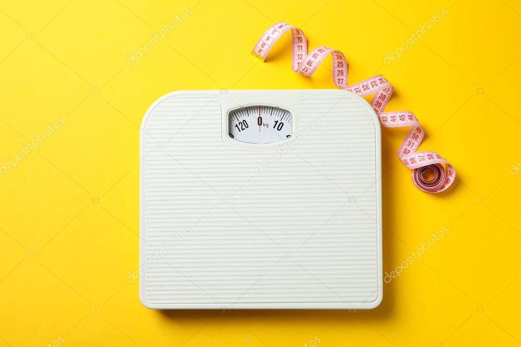 Scales and measuring tape on yellow background. Weight loss concept