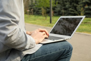 Bilgisayarlı adam parkta çalışıyor. Açık hava işi.