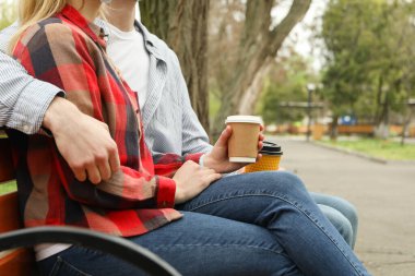 Parkta oturan ve kahve içen çift.