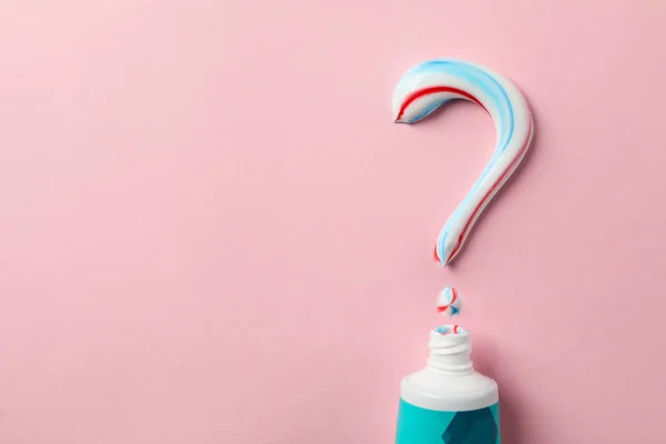 Question mark made of toothpaste and tube on pink background, copy space