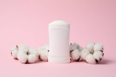 Pembe arkaplanda vücut deodorantı ve pamuk, metin için boş alan