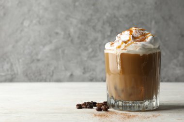 Ahşap masaya krema dökülmüş bir bardak buzlu kahve.