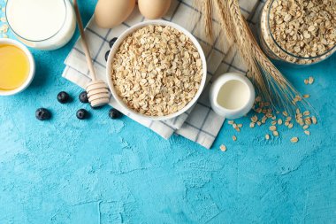 Mavi arka planda yulaf ezmesi parçaları olan kompozisyon. Kahvaltı hazırlıyorum.