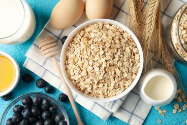 Mavi arka planda yulaf ezmesi parçaları olan kompozisyon. Kahvaltı hazırlıyorum.