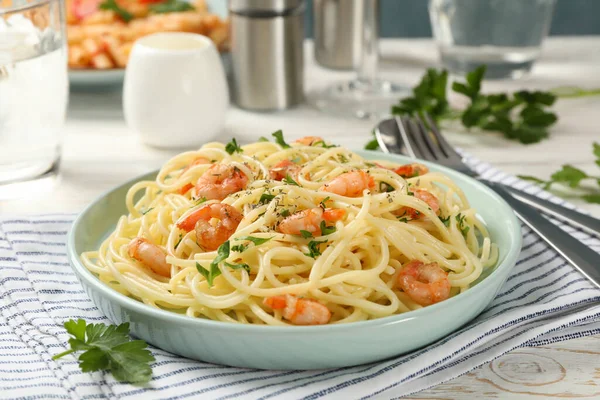 Composition with plate of tasty pasta with shrimps on wooden background