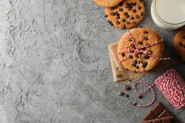Gri masa üzerinde çipli kurabiye ve sütle kompozisyon