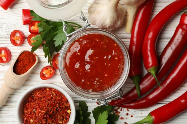 Composition with red hot sauce and ingredients on wooden background