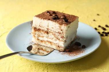 Sarı arka planda lezzetli tiramisu tabağı. Lezzetli tatlı