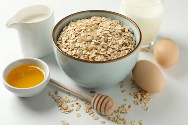 Beyaz arka planda yulaf ezmesi parçaları olan kompozisyon, yakın çekim. Kahvaltı hazırlıyorum.