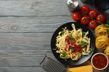 Lezzetli makarna ve ahşap arka planda yemek pişirmek için malzemeler içeren kompozisyon