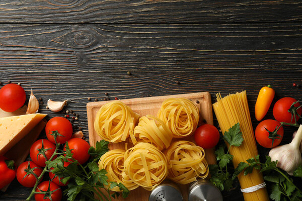 Composition with pasta and ingredients for cooking on wooden background, top view